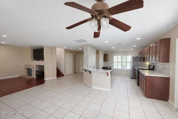 a large kitchen with stainless steel appliances kitchen island granite countertop a refrigerator a stove top oven and a sink