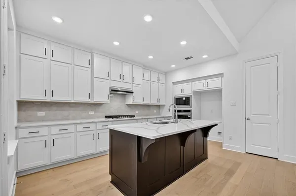 a kitchen with a sink a stove a refrigerator and white cabinets