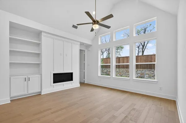 a view of an empty room with a window and a kitchen