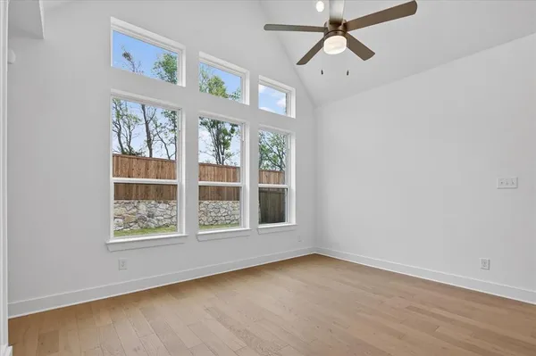 an empty room with wooden floor chandelier and windows