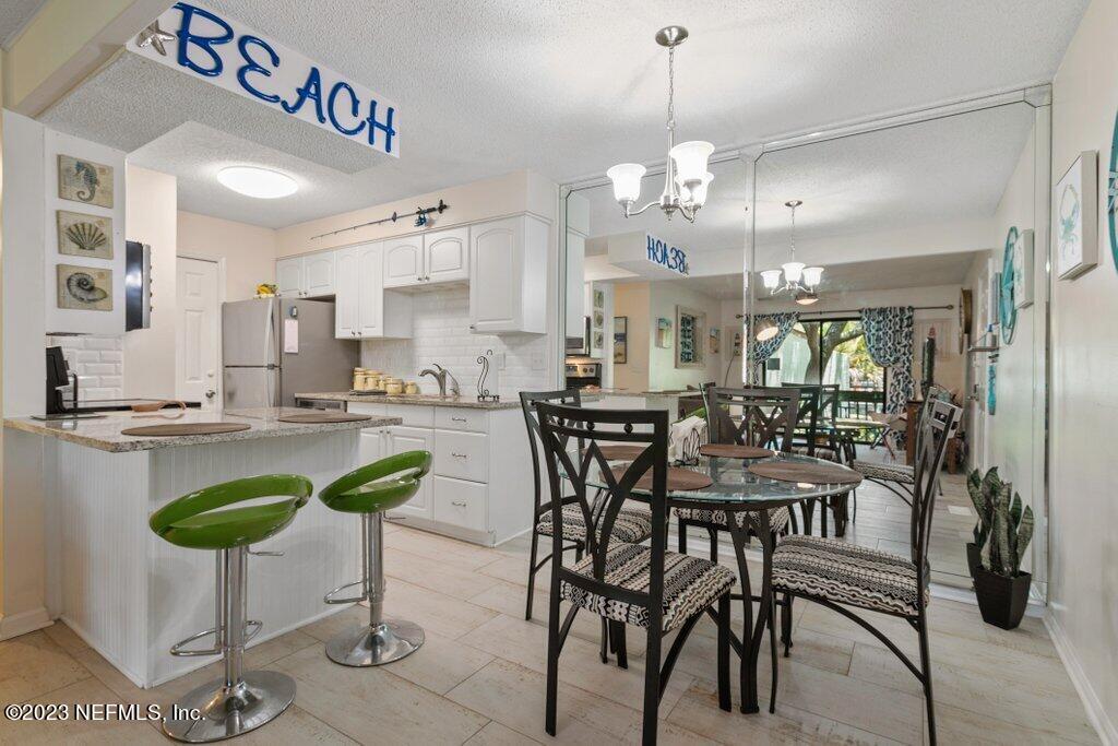 2694 Forest Ridge Drive, Unit 4A Fernandina Beach, FL 32034 - Photo 11 of 38 a kitchen with a table chairs and white cabinets