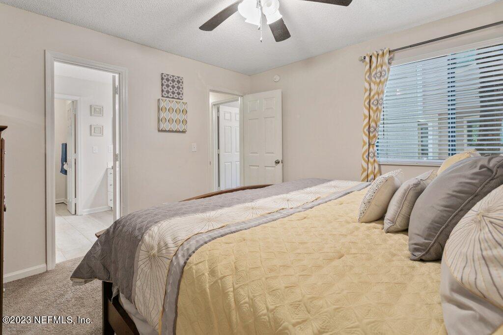 2694 Forest Ridge Drive, Unit 4A Fernandina Beach, FL 32034 - Photo 19 of 38 a bedroom with a bed and a chandelier