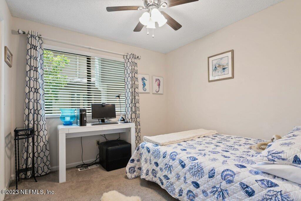 2694 Forest Ridge Drive, Unit 4A Fernandina Beach, FL 32034 - Photo 24 of 38 a bedroom with a bed and a chandelier