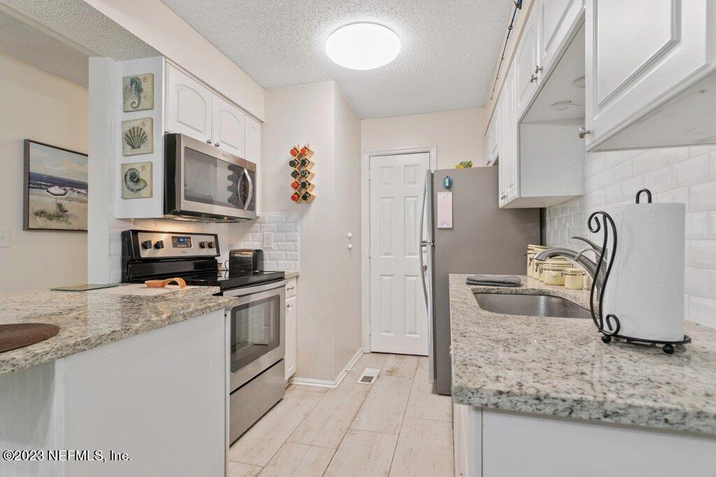 2694 Forest Ridge Drive, Unit 4A Fernandina Beach, FL 32034 - Photo 8 of 38 a kitchen with granite countertop a sink stove and refrigerator