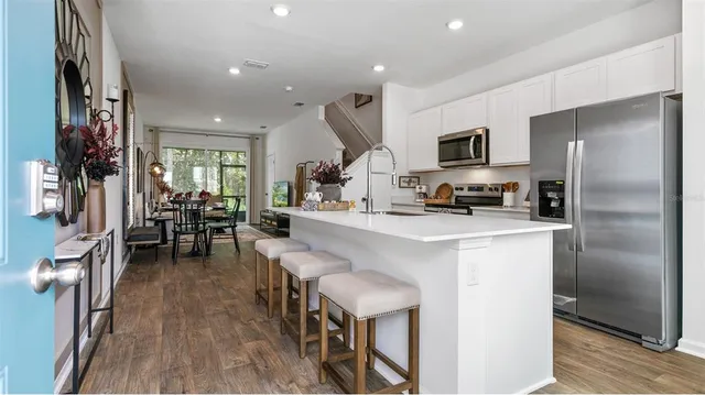 a kitchen with stainless steel appliances kitchen island granite countertop a refrigerator a stove a microwave oven a sink with island and chairs