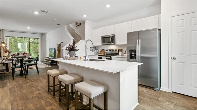 a kitchen with stainless steel appliances kitchen island a refrigerator a table and chairs in it