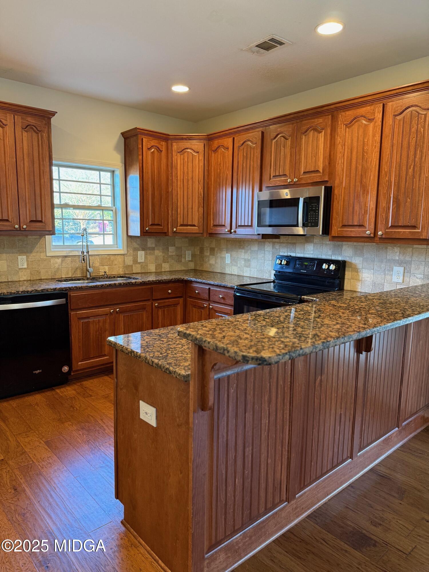 149 Presidents Way Forsyth, GA 31029 - Photo 6 of 26 a kitchen with stainless steel appliances granite countertop wooden cabinets a stove top oven a sink and dishwasher with wooden floor