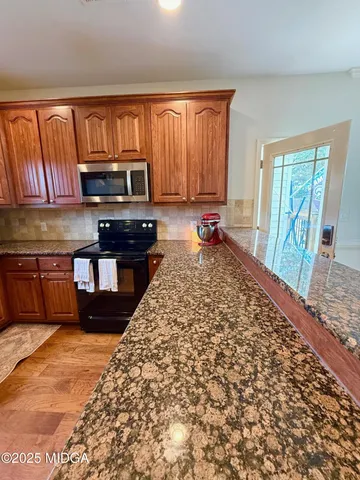 a kitchen with stainless steel appliances granite countertop a stove a sink and a microwave