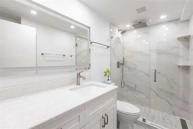 a bathroom with a sink a toilet a large mirror and shower