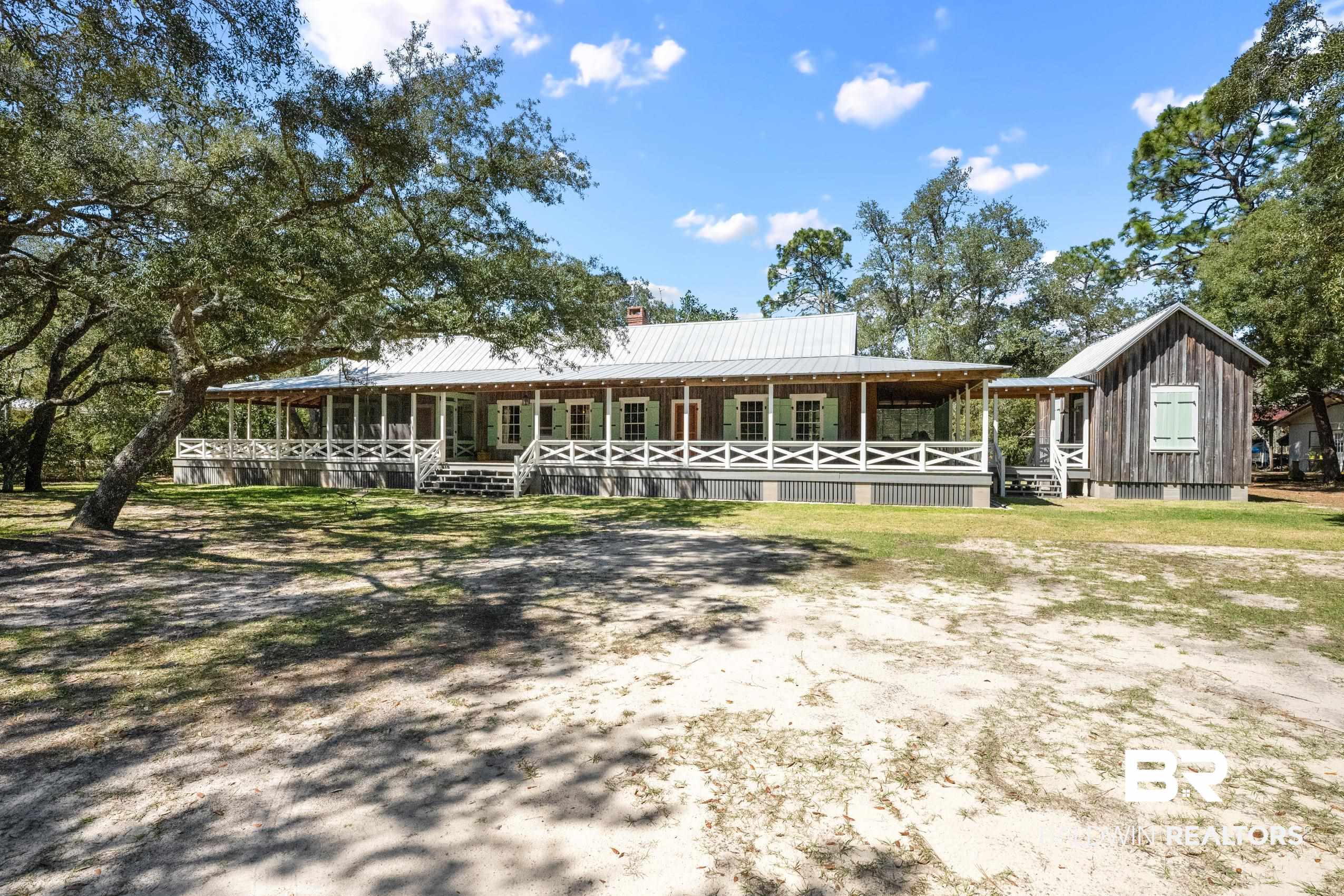 30671 Magnolia Street Elberta, AL 36530 - Photo 1 of 68 View of front of house with metal roof, covered porch, a chimney, and board and batten siding