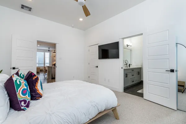 a bedroom with a bed and a flat tv screen on dresser