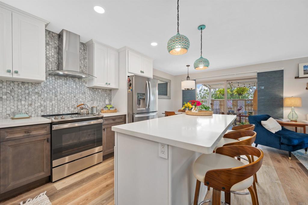 315 Volney Lane Encinitas, CA 92024 - Photo 17 of 51 a kitchen with stainless steel appliances kitchen island granite countertop a stove a sink a dining table and chairs with wooden floor