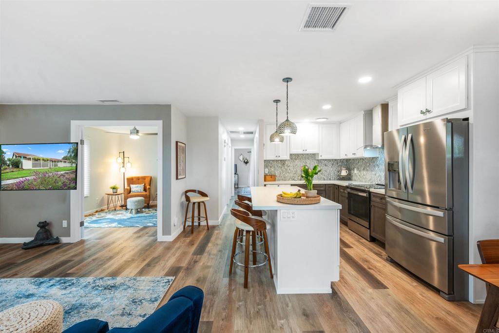 315 Volney Lane Encinitas, CA 92024 - Photo 10 of 51 a kitchen with a refrigerator a stove top oven a sink dishwasher and white cabinets with wooden floor
