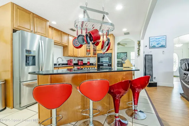 a kitchen with stainless steel appliances granite countertop a dining table chairs and a refrigerator