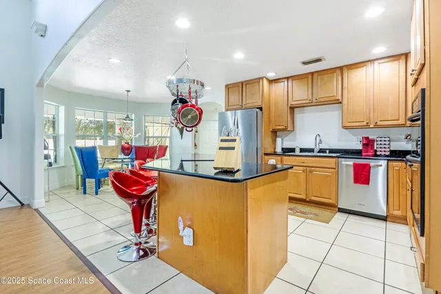 a kitchen with stainless steel appliances kitchen island granite countertop a refrigerator a stove and a sink