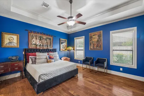 a bedroom with a large bed a chandelier and windows