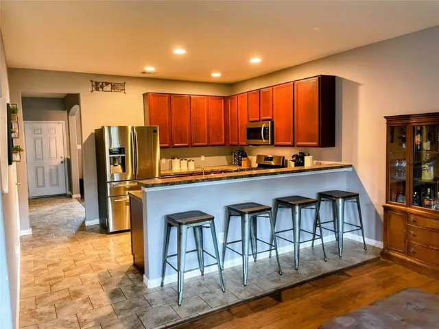 a kitchen with stainless steel appliances granite countertop a table chairs and a refrigerator
