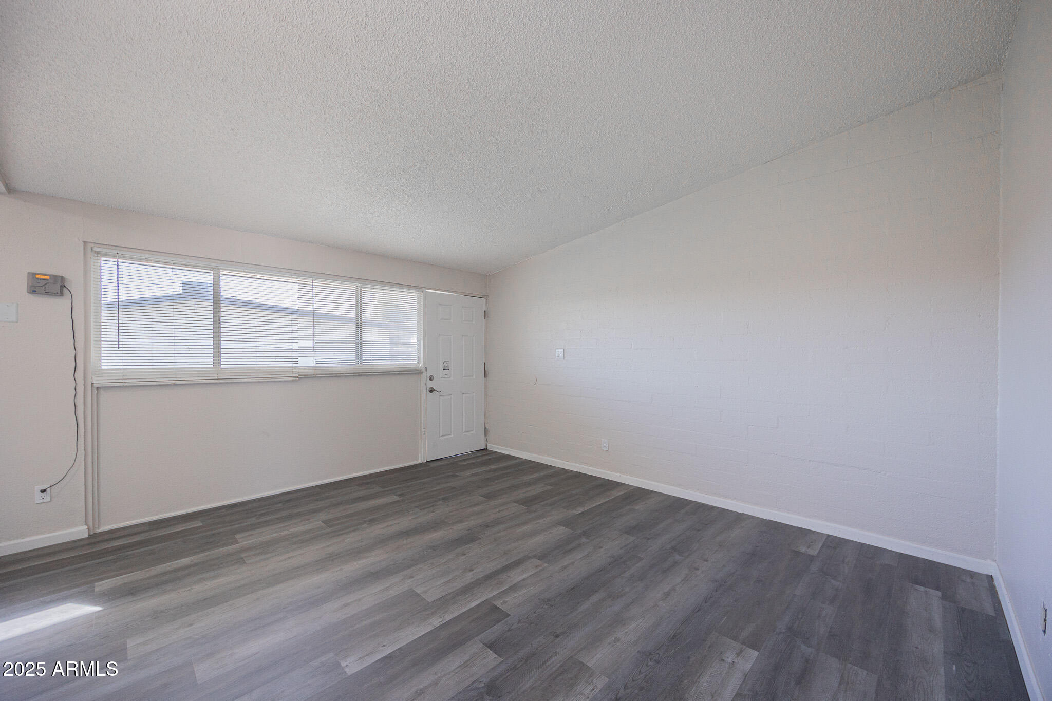 2123 West Devonshire Avenue, Unit 14 Phoenix, AZ 85015 - Photo 6 of 13 an empty room with wooden floor and windows