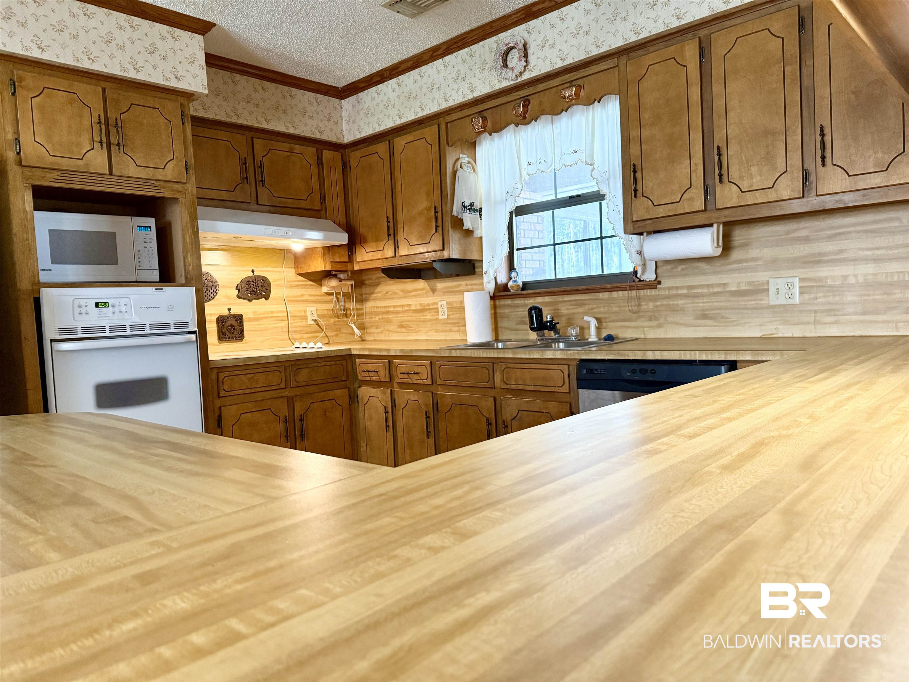 98 Evans Avenue Brewton, AL 36426 - Photo 5 of 18 Kitchen featuring wood finish cabinetry, white appliances, a textured ceiling, and ornamental molding