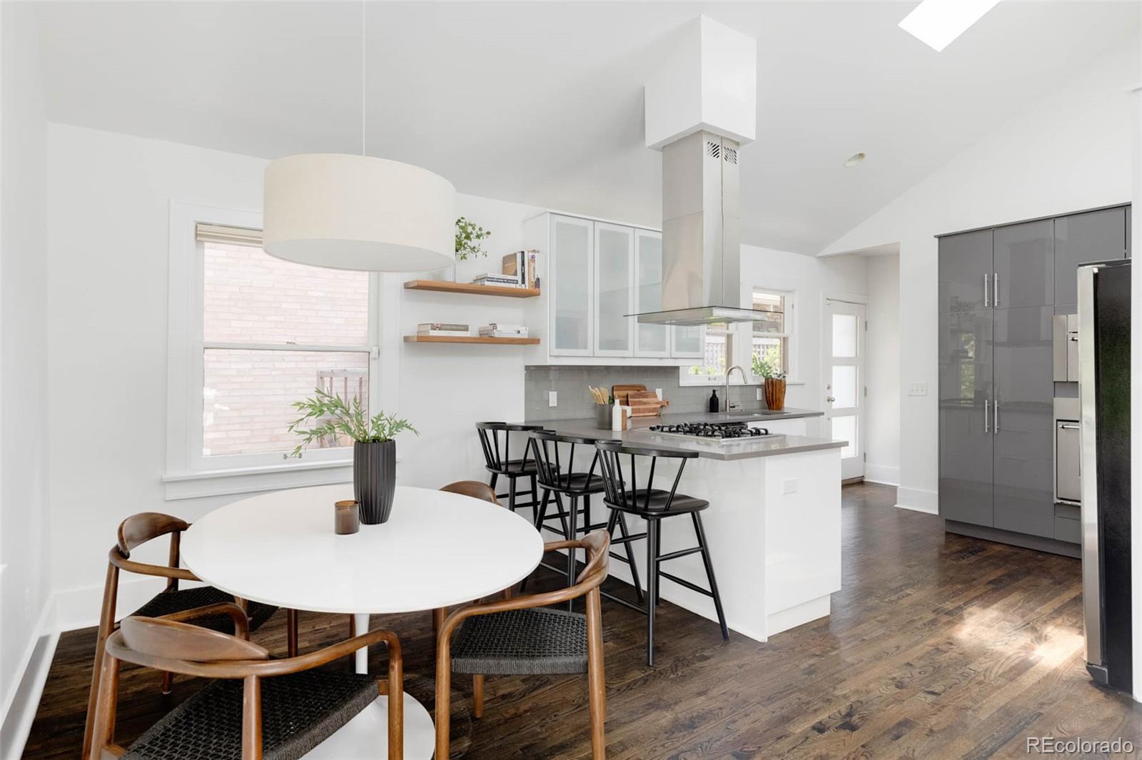 725 Monroe Street Denver, CO 80206 - Photo 10 of 33 a kitchen with kitchen island a dining table and chairs