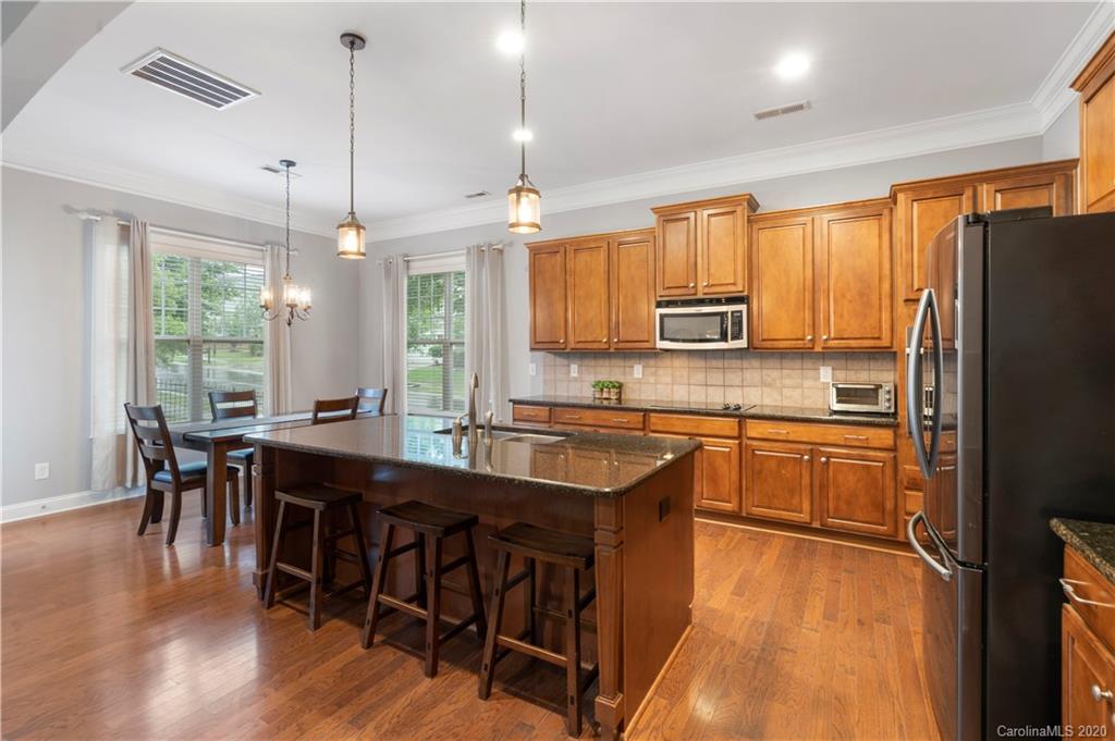 2011 Fallondale Road Waxhaw, NC 28173 - Photo 7 of 39 a kitchen with stainless steel appliances granite countertop a stove a refrigerator a sink a dining table and chairs with wooden floor