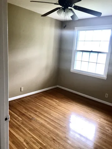 an empty room with a window and ceiling fan
