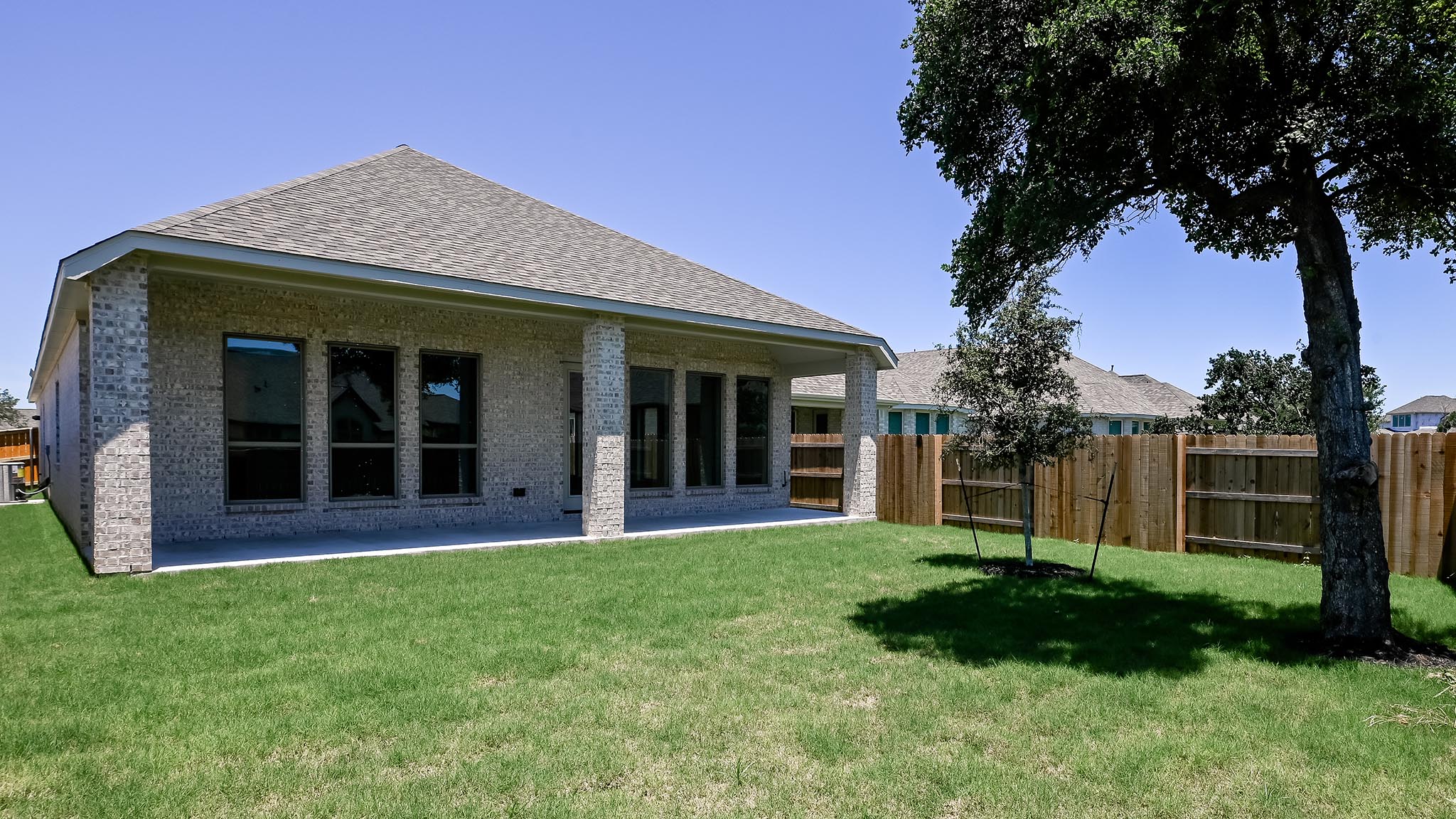 126 Basket Flower Loop Kyle, TX 78640 - Photo 24 of 29 a view of brick house with a large window and a yard with plants and large trees