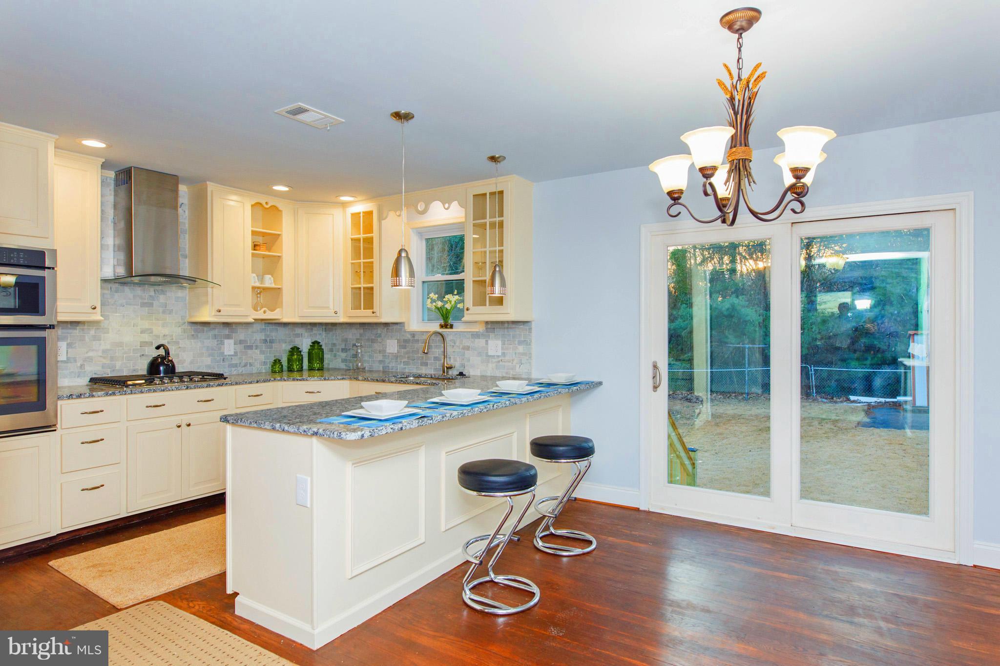 630 Warwick Road Baltimore, MD 21229 - Photo 6 of 23 a kitchen with a stove a chandelier cabinetry and a dining table