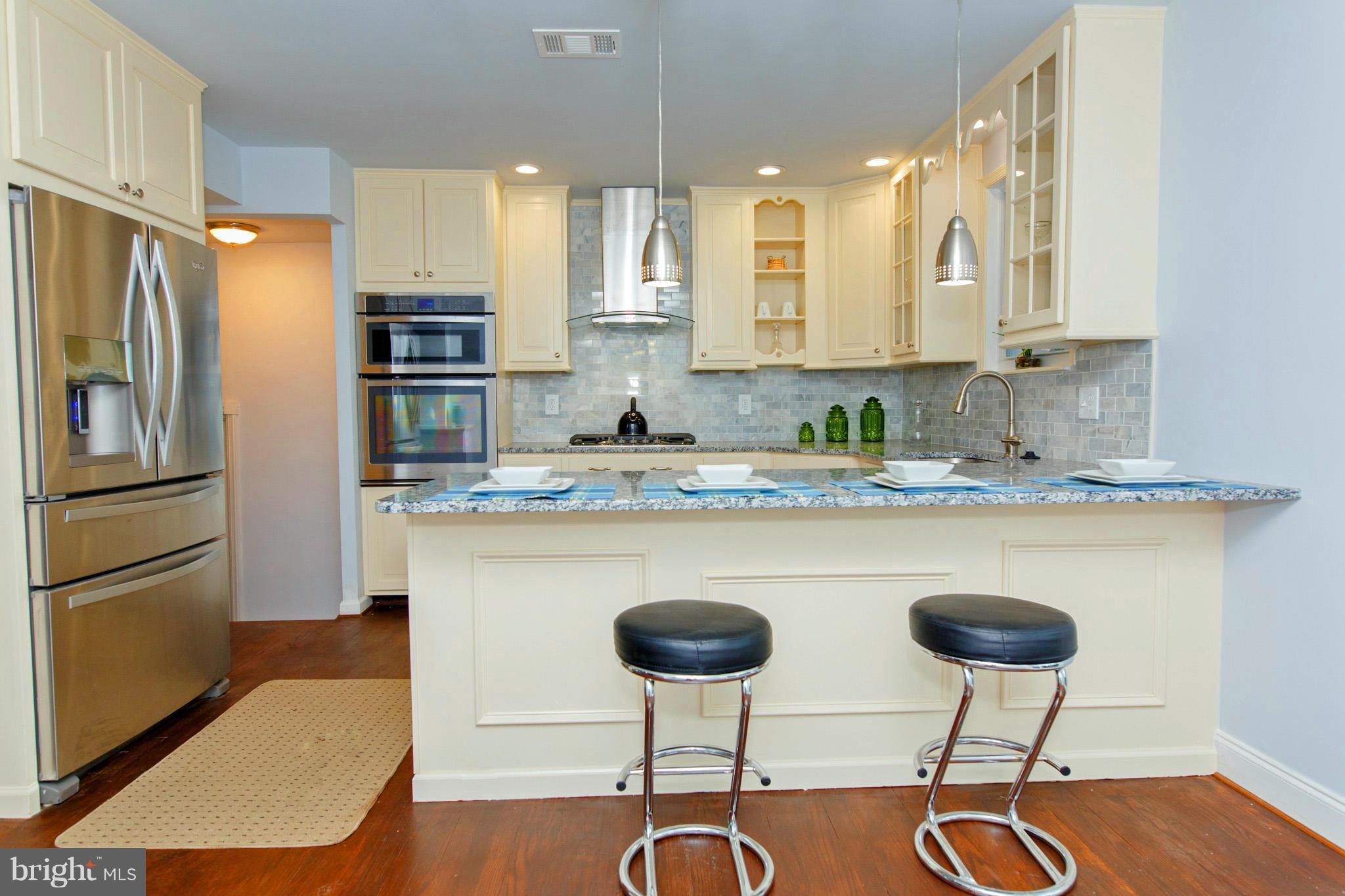 630 Warwick Road Baltimore, MD 21229 - Photo 8 of 23 a kitchen with stainless steel appliances granite countertop a refrigerator a stove a sink counter tops and chairs with wooden floor