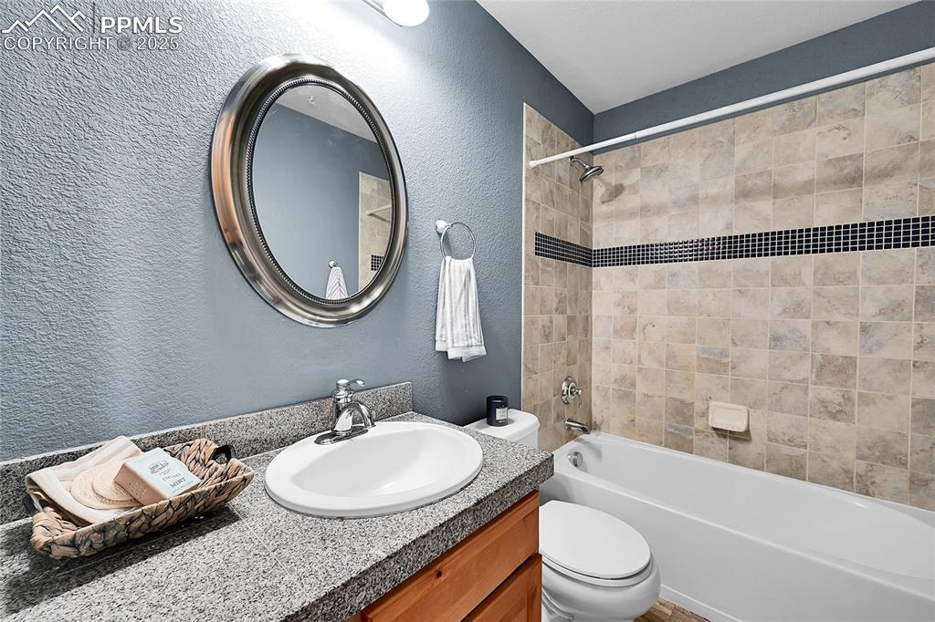 16540 Mesquite Road Peyton, CO 80831 - Photo 32 of 50 a bathroom with a granite countertop sink mirror vanity and a toilet