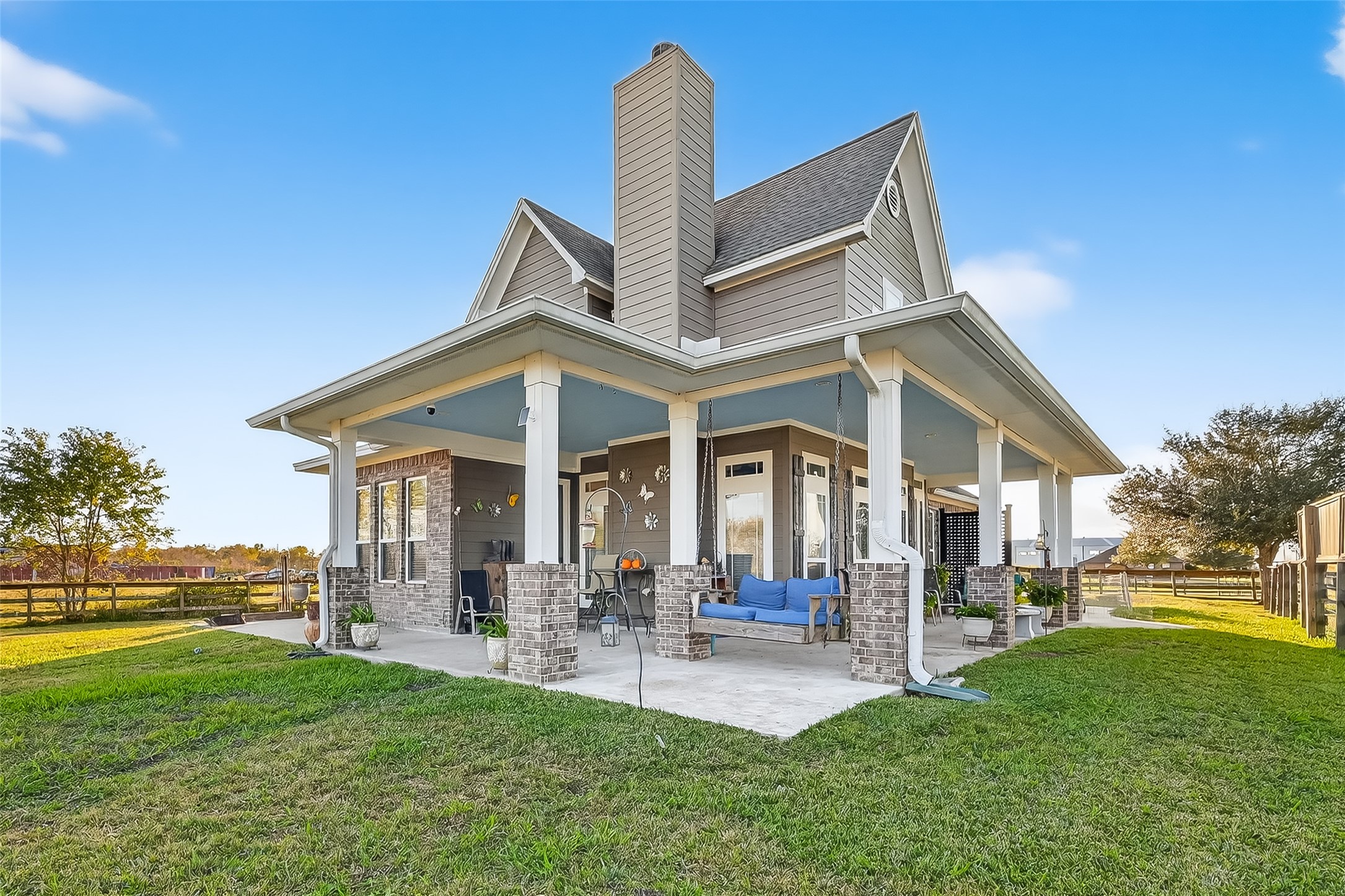 912 County Road 340 Angleton, TX 77515 - Photo 6 of 50 Charming two-story home with a spacious wrap around porch, brick accents, and a cozy swing. Surrounded by lush green lawn and set in a peaceful, open area, perfect for relaxation and outdoor living.