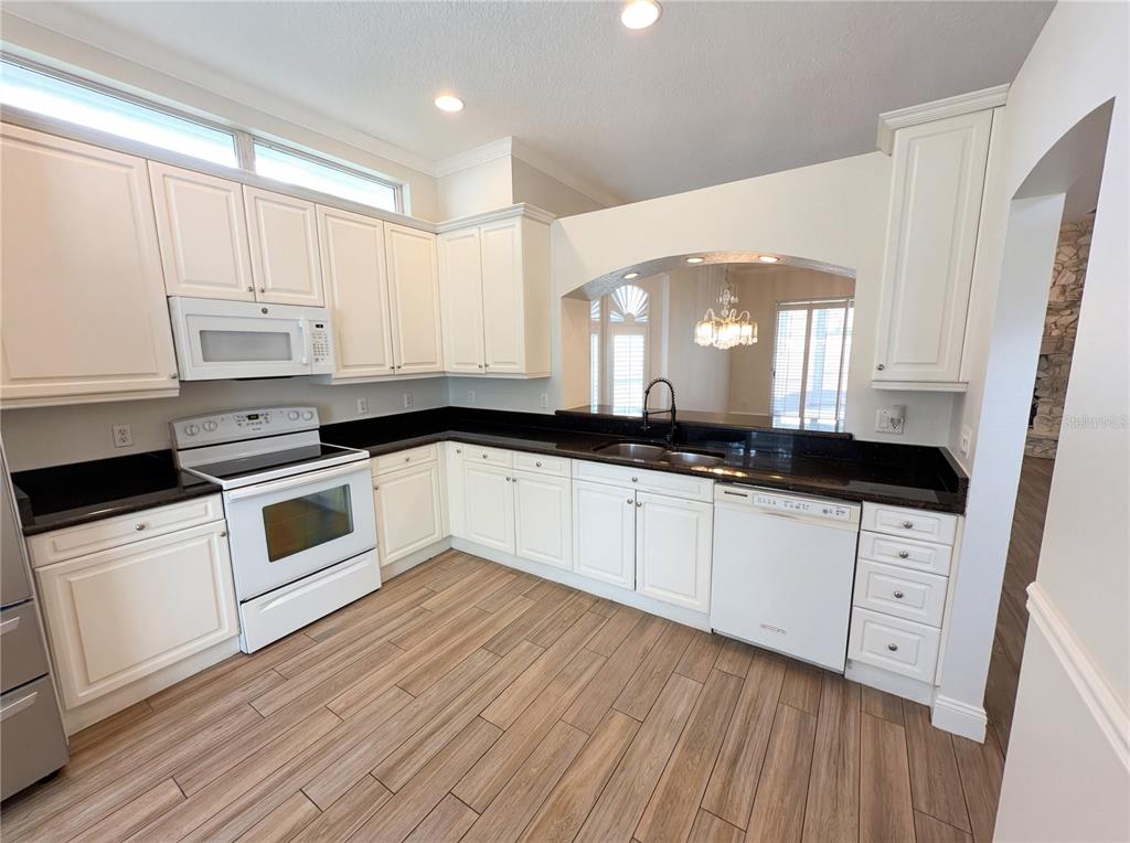 448 MacGregor Road Winter Springs, FL 32708 - Photo 15 of 26 a kitchen with granite countertop a stove a sink and white cabinets with wooden floor