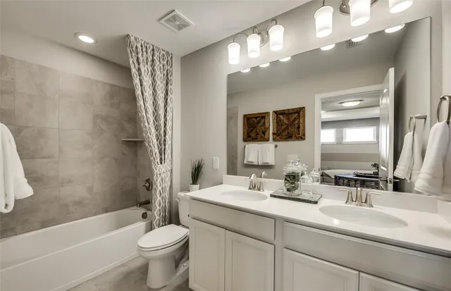 a bathroom with a double vanity sink toilet mirror and bathtub