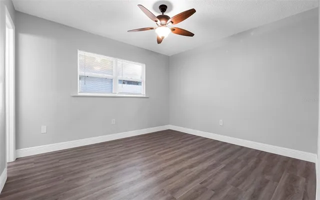 a view of an empty room with window and wooden floor