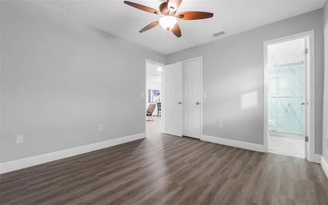 an empty room with wooden floor chandelier fan and closet area