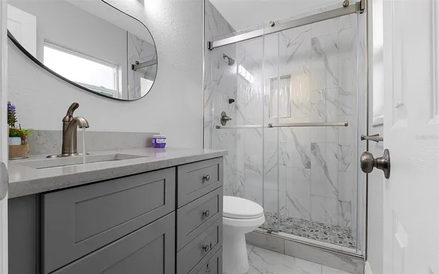 a bathroom with a granite countertop sink toilet and shower