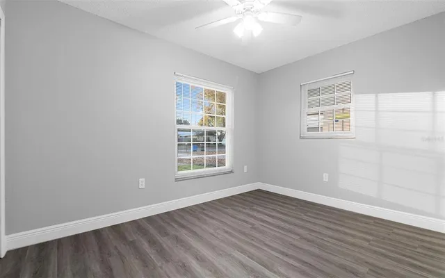 an empty room with wooden floor and windows