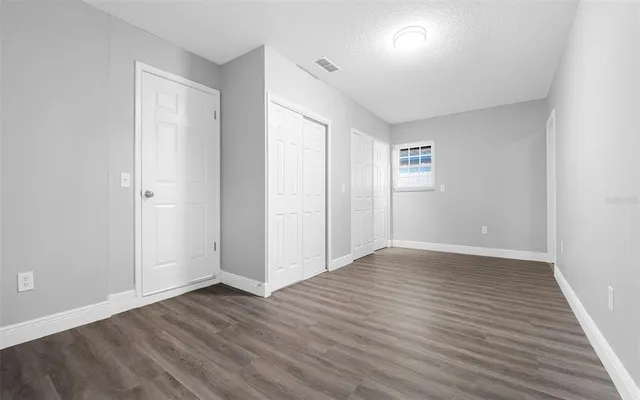 an empty room with wooden floor & windows