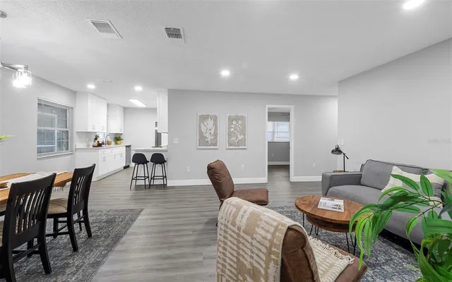 a living room with furniture a wooden floor and kitchen view