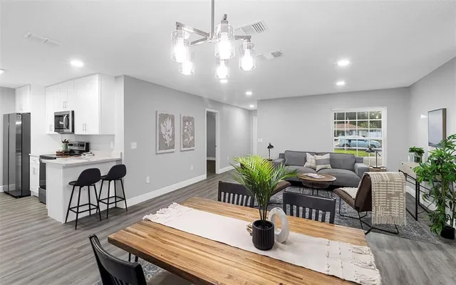 a living room with furniture potted plant and open kitchen view