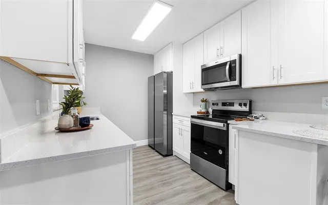 a kitchen with stainless steel appliances a sink a stove top oven a refrigerator a counter space and cabinets