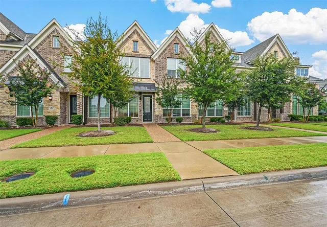 a front view of a house with a yard and potted plants