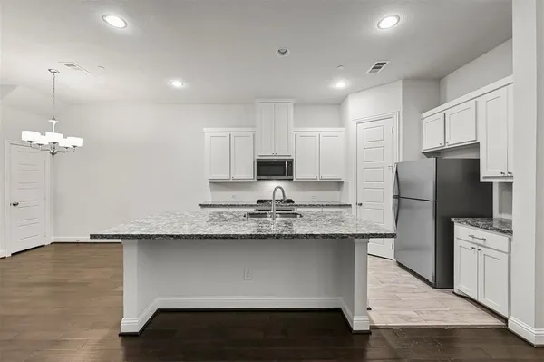 a kitchen with stainless steel appliances granite countertop a sink a stove a refrigerator a center island and wooden floor