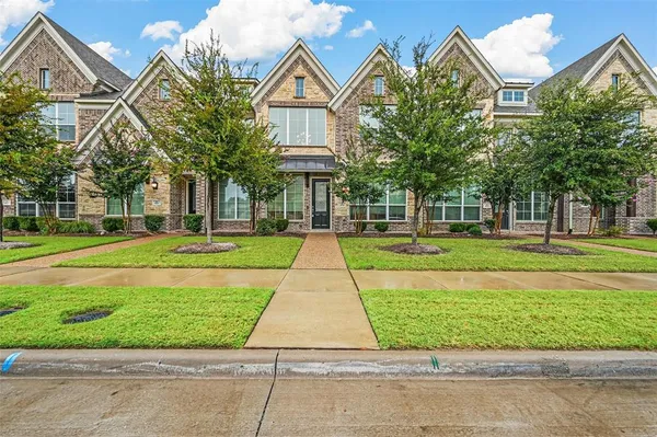 a front view of a house with a yard and potted plants