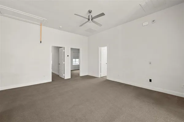an empty room with chandelier fan and windows