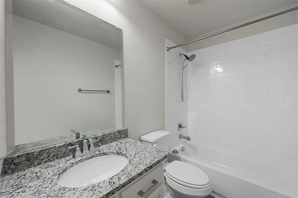 a bathroom with a granite countertop sink toilet a mirror and shower