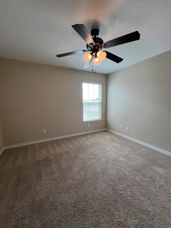 an empty room with windows and chandelier fan