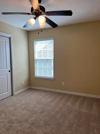 an empty room with a chandelier fan and windows