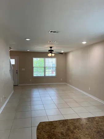 an empty room with windows and ceiling fan