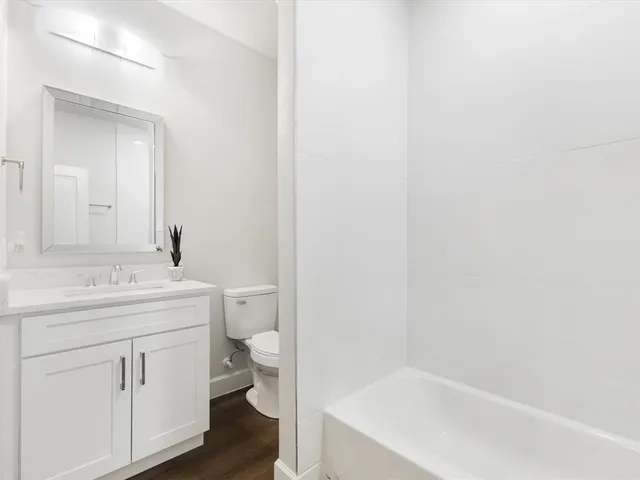 a bathroom with a granite countertop sink and a toilet